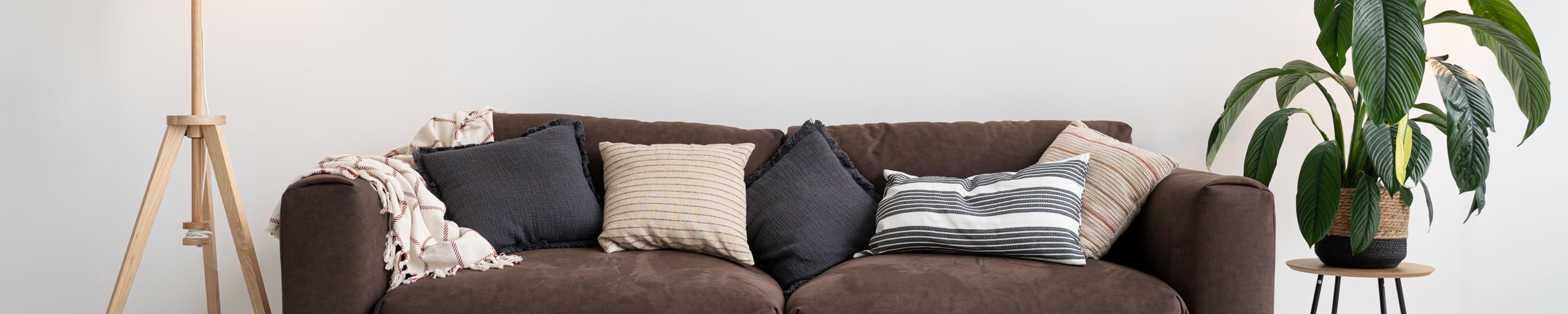 Ruhiger Wohnraum mit Sofa, Textilien und Pflanze als hi-home Markenstimmung